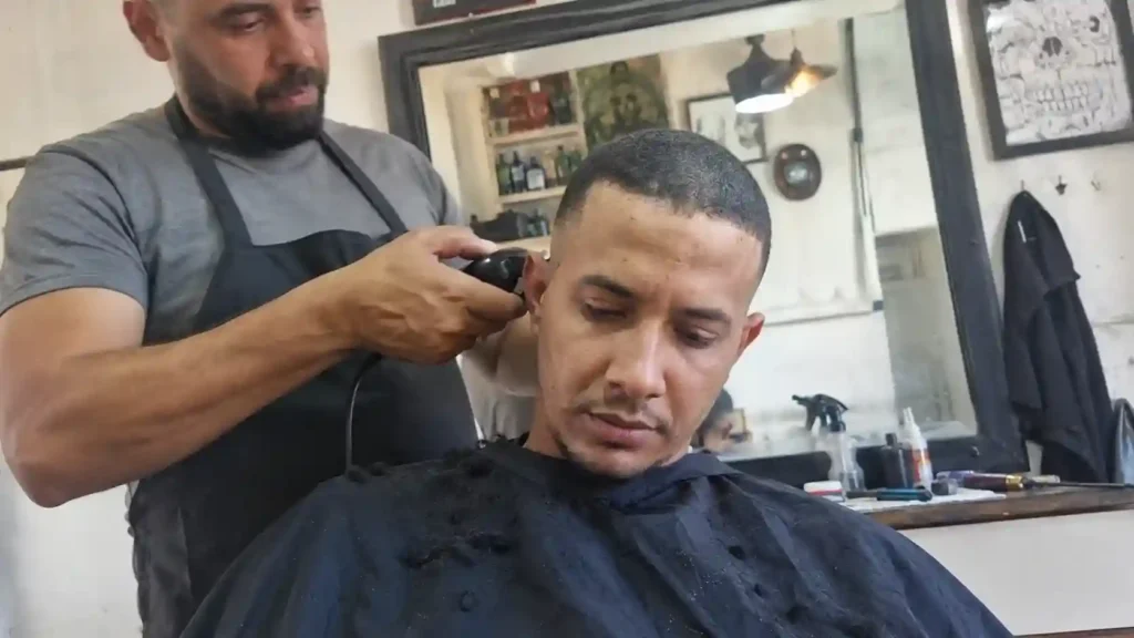 Barbier schneidet Kunden mit Maschine einen Buzz Cut im Salon