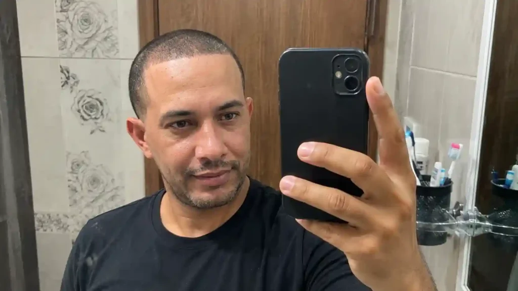 Mann mit Geheimratsecken und frischem Buzz Cut vor dem Spiegel