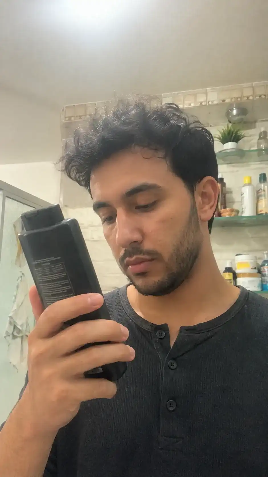 Mann liest das Etikett eines Shampoos für Männer
