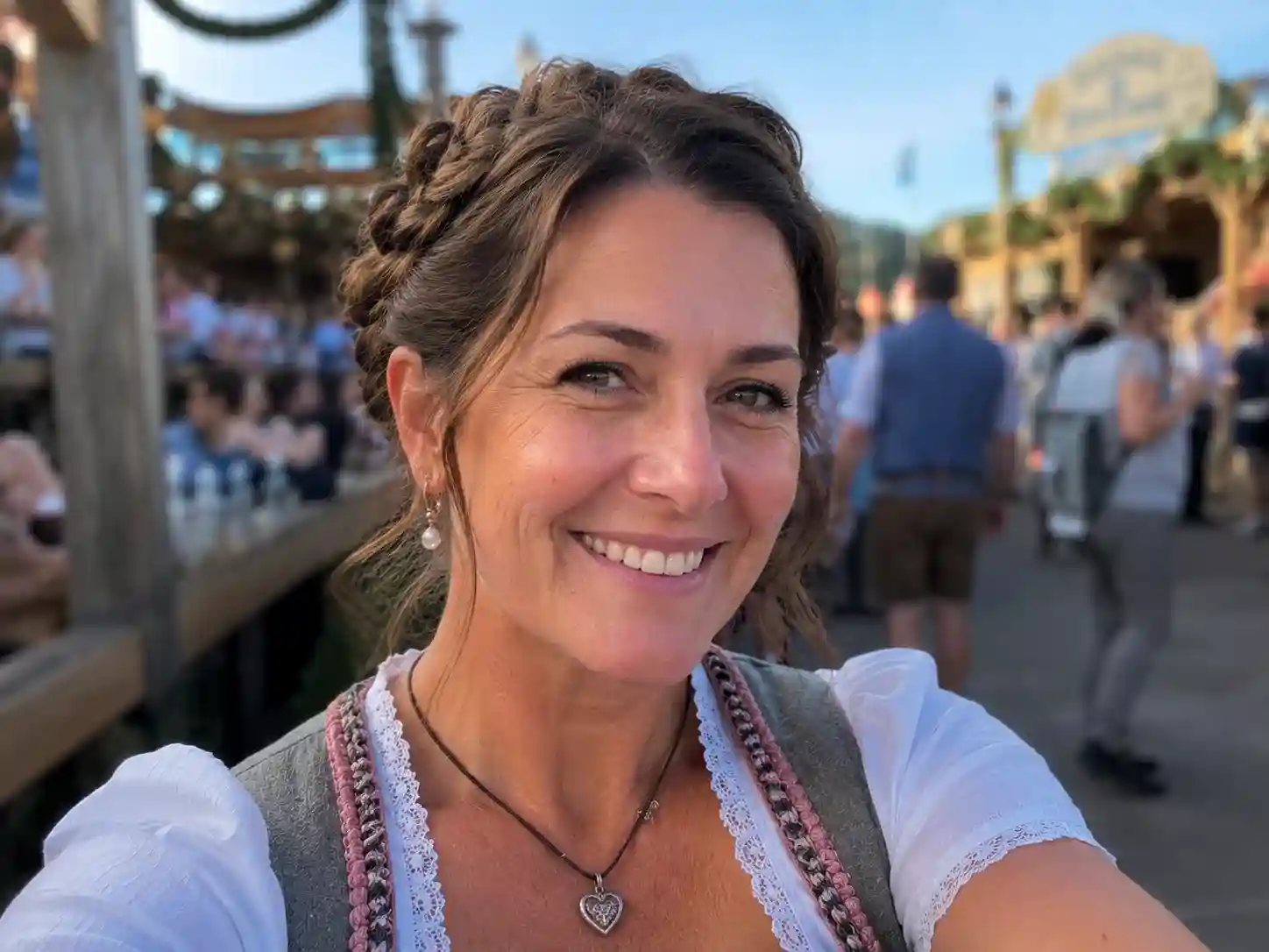 Frau mit geflochtener Frisur schulterlang und Dirndl beim Oktoberfest im Freien