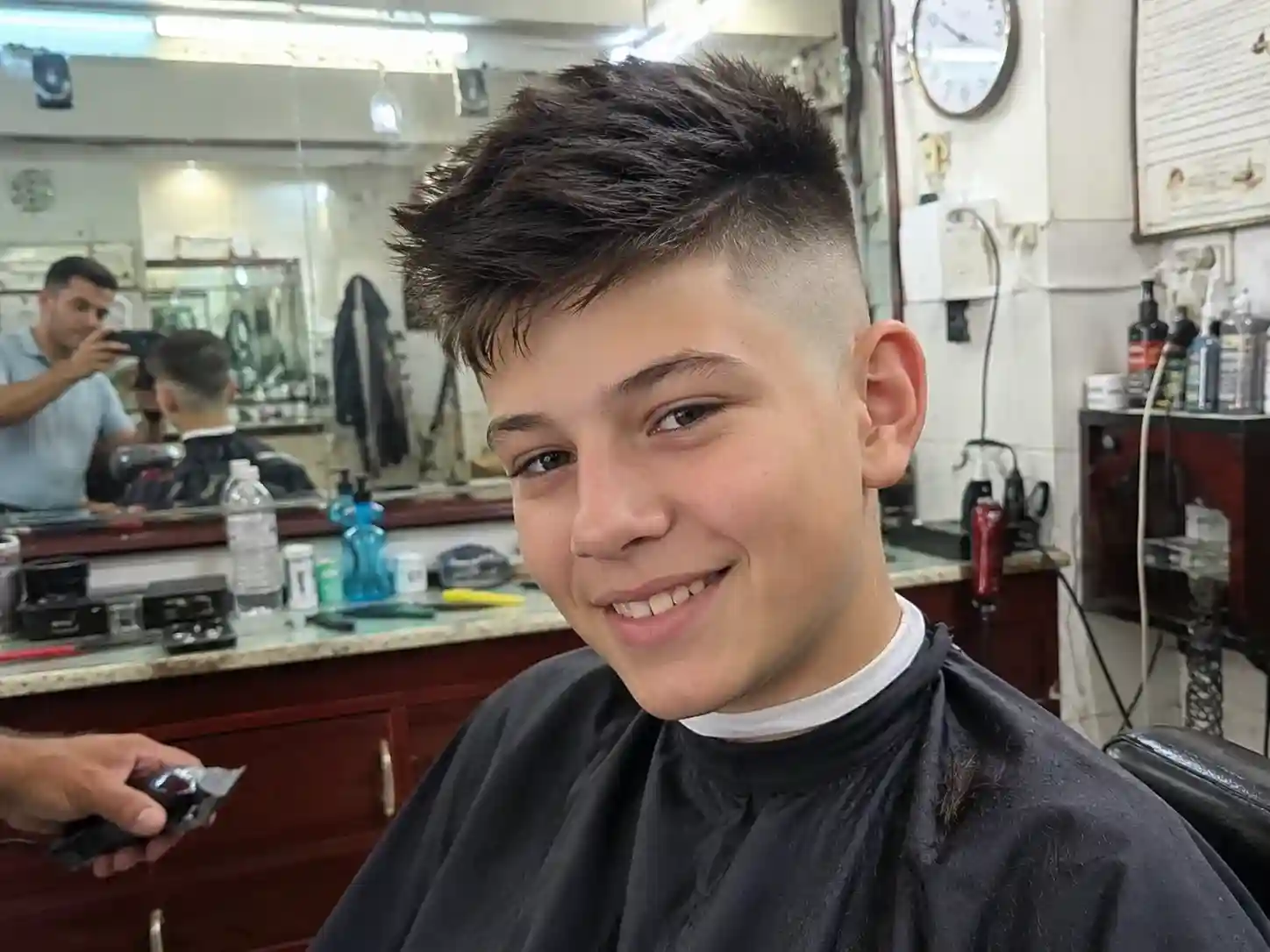 Junge mit frisch geschnittenem Fade beim Friseur, eine besonders pflegeleichte Frisur für Jungs ab 13 Jahren