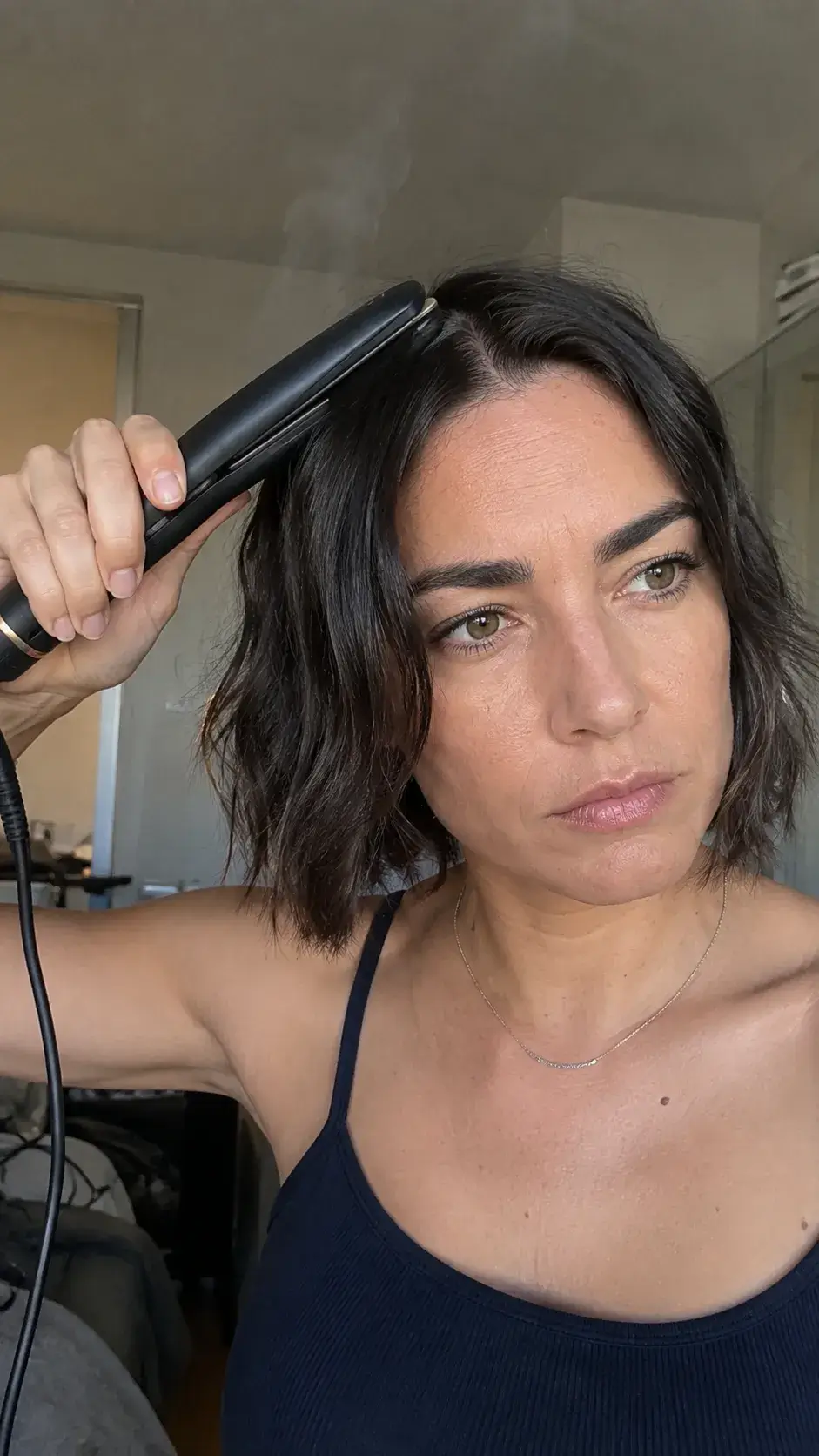Frau glättet kurze Haare vorsichtig mit einem kleinen Glätteisen
