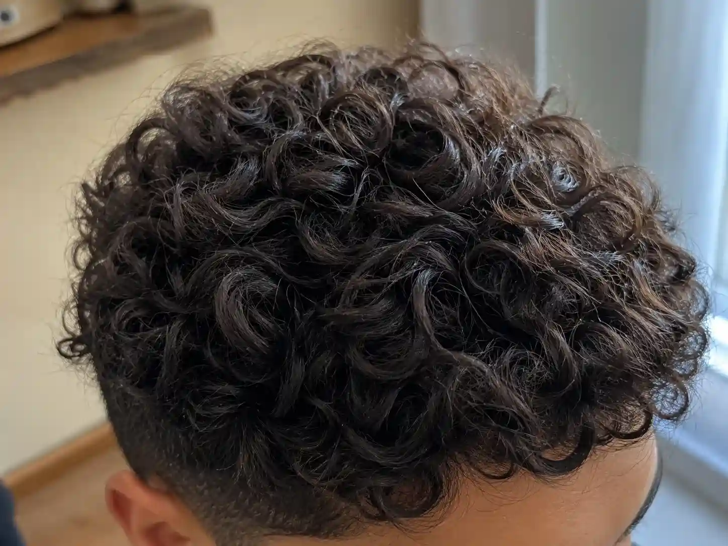 Natürliche Locken bei einer coolen Frisur für Jungs ab 10 mit definierter Textur
