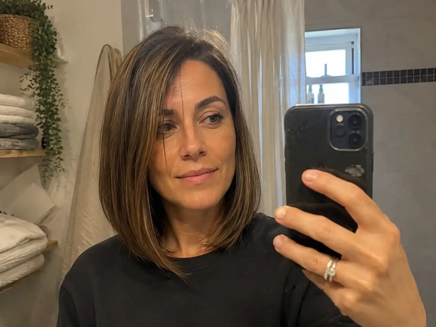 Frau mit Long-Bob-Frisur schulterlang fotografiert sich morgens vor dem Badezimmerspiegel