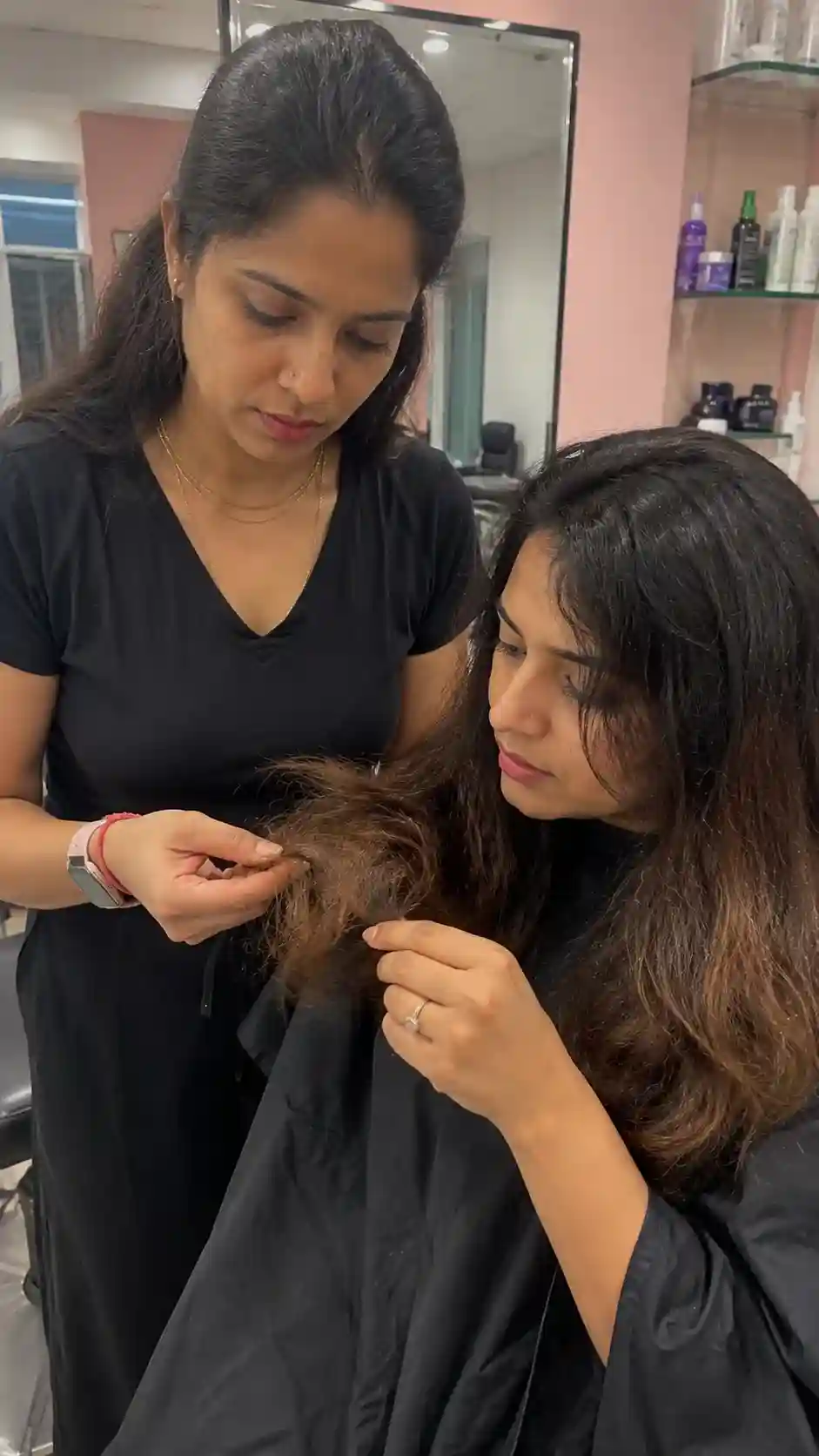Friseurin begutachtet die Haarspitzen einer Kundin im Salon